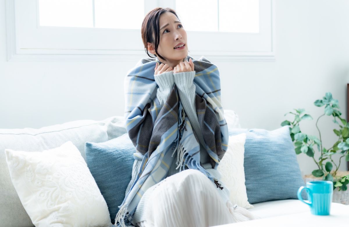 部屋でブランケットを羽織る女性