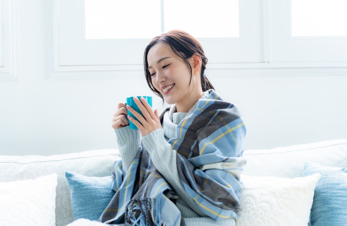 カップを持ちソファでくつろぐ女性