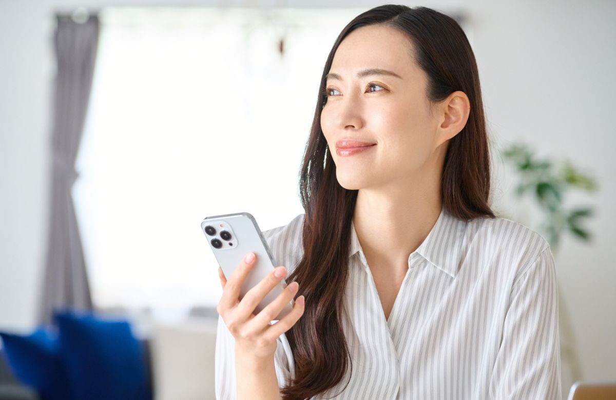 スマートフォンを片手に前向きな表情の女性